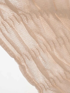 Detailed macro view of the delicate apricot pleated mesh fabric and fine knit texture