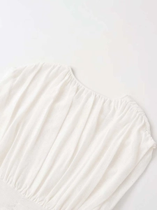 Detail shot of a white pleated sleeveless knit vest with a round neck and fine texture