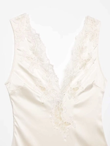 Close-up of ivory satin bodysuit with delicate lace trim and deep V-neckline