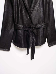 Close-up of black faux leather jacket with pebble texture and belted waist detail