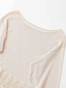 Detailed close-up of cream knit sweater showing fine texture and wide neckline details