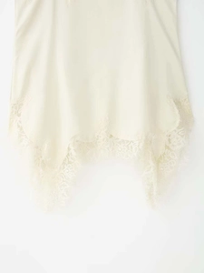 Close-up of cream camisole featuring delicate eyelash lace trim and silky fabric