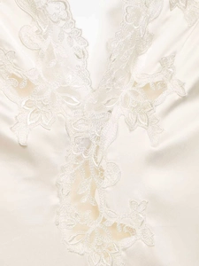 Detail of white satin bodysuit showing intricate floral lace embroidery on V-neckline