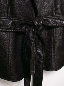 Detail view of waist tie on black faux leather coat with textured pebble grain finish