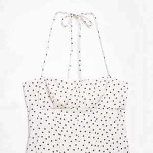 Haut licou blanc chic à pois noirs avec poitrine froncée et fermeture à nouer au cou
