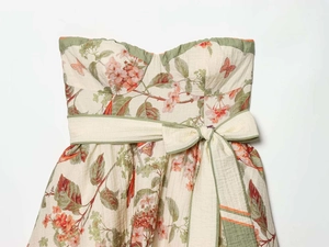 Detail of a floral strapless dress with a large waist bow and olive green edge piping