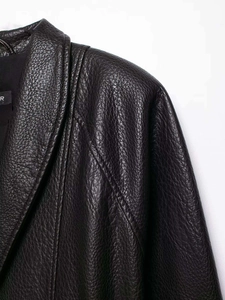 Detail view of black faux leather jacket showing lychee grain texture and shoulder stitching