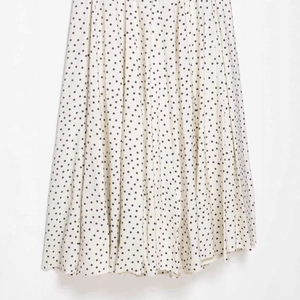 Jupe midi plissée à pois blancs et noirs, design élégant et minimaliste à taille haute