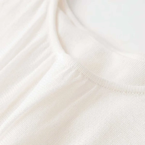 Close-up of cream white sun pleated sleeveless knit vest with fine mesh texture detail
