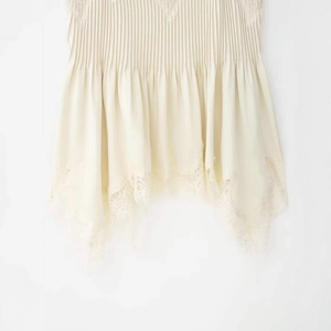 Elegant apricot camisole with pleated fabric and delicate lace trim hem details