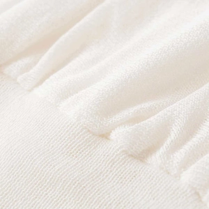 Detailed macro shot of white pleated knit tank top featuring ribbed hem and fine texture