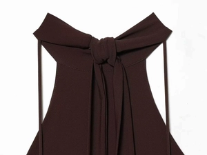 Detail of the dark brown halter neckline with tied bow and elegant pleated fabric texture