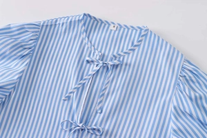 Detail of blue and white striped poplin shirt featuring double tie bow neckline and S size tag