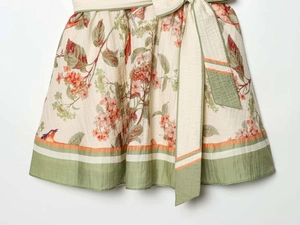 Close-up of strapless dress fabric with pink cherry blossoms and colorful bird prints