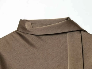 Detail of asymmetrical neckline and textured satin fabric on dark brown dress
