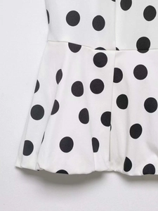 Gros plan sur un tissu blanc à pois noirs avec des détails de volants délicats