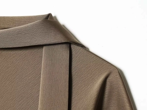Detailed macro view of brown satin dress neckline featuring elegant bow tie and twill texture