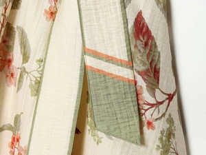 Close-up of floral print cotton-linen dress with green piping and striped waist belt detail