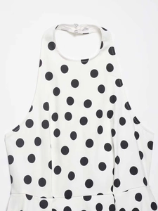 Détail du décolleté dos nu à pois avec fermeture à deux boutons sur tissu blanc