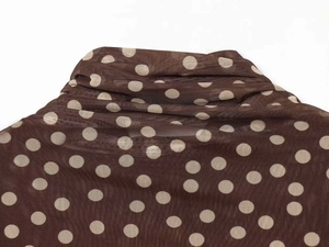 Detail of brown mesh turtleneck top featuring white polka dots and sheer breathable fabric