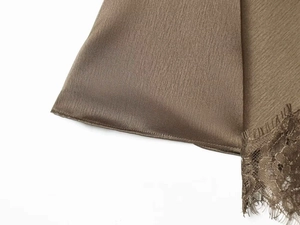 Detail of bronze satin dress showing refined lace trim and high-quality hem stitching