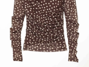 Close-up of sheer mesh polka dot top featuring ruched body and ruffled sleeve details
