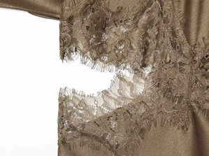 Detailed macro view of delicate lace trim on coffee-colored satin fabric dress