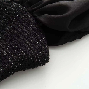 Detail of black tweed fabric texture contrast with smooth satin pleats on the strap vest