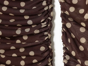 Detailed macro view of dark brown mesh fabric with beige polka dots and elegant ruching