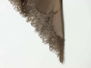Close-up of brown satin fabric with delicate eyelash lace detailing on the edges
