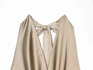 Detail of champagne gold satin halter neck dress featuring a refined bow-tie neckline