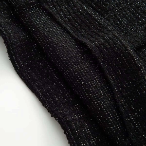 Close-up of black tweed fabric with silver metallic glitter and textured knit details