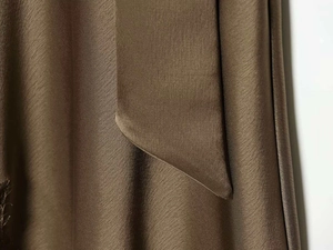 Detailed view of bronze satin fabric with lace trim and elegant draped necktie