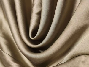 Detailed view of the glossy champagne satin fabric with soft drapes and smooth texture