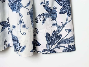 Détail de l'imprimé floral sur tissu blanc avec feuilles bleues et motifs botaniques