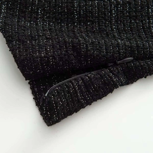 Close-up of black tweed fabric with metallic silver threads and hidden zipper detail