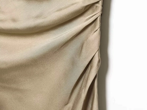 Detailed view of champagne satin fabric with elegant side ruching and silky texture
