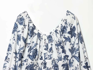 Détail du col en V avec taille smockée et imprimé floral bleu sur robe d'été blanche