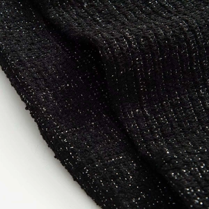 Macro shot of black tweed fabric with shimmering silver lurex threads and textured weave