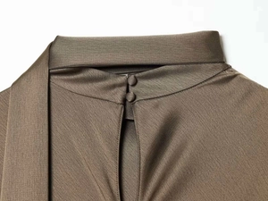 Detail of stand collar with hollow cutout, fabric buttons and ties on satin dress