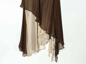 Detailed view of asymmetric ruffled hem with white polka dots on brown chiffon fabric