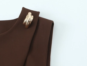 Detail of coffee brown twill vest with an elegant golden twisted metal buckle on shoulder