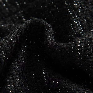 Macro detail of black knit fabric with shimmering silver sequins and sparkling metallic threads