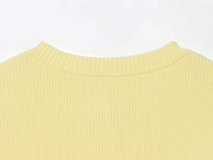Close-up of cream yellow knitted sweater featuring ribbed texture and round neckline details