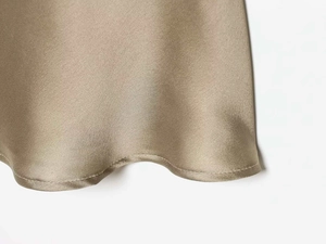 Detail of satin fabric showing fine stitching and smooth champagne silk texture