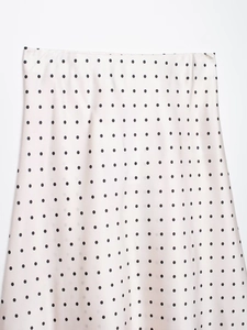 Vue détaillée de pois noirs sur tissu satiné blanc avec une texture soyeuse et lisse