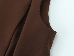 Close-up of dark brown textured fabric and armhole stitching on sleeveless vest suit