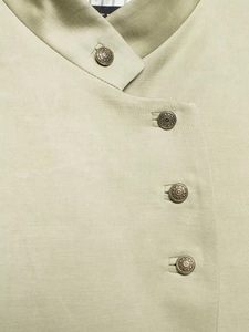 Close-up of textured fabric and vintage bronze metal buttons on a grey-green blazer