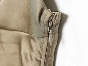 Close-up of invisible teardrop zipper on olive satin halter dress with smooth stitching