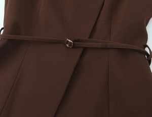 Detail of a brown woven vest with a matching thin belt and a small golden metal buckle